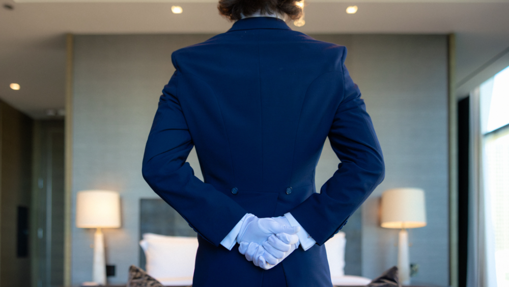 Butler standing in a room with hands behind his back