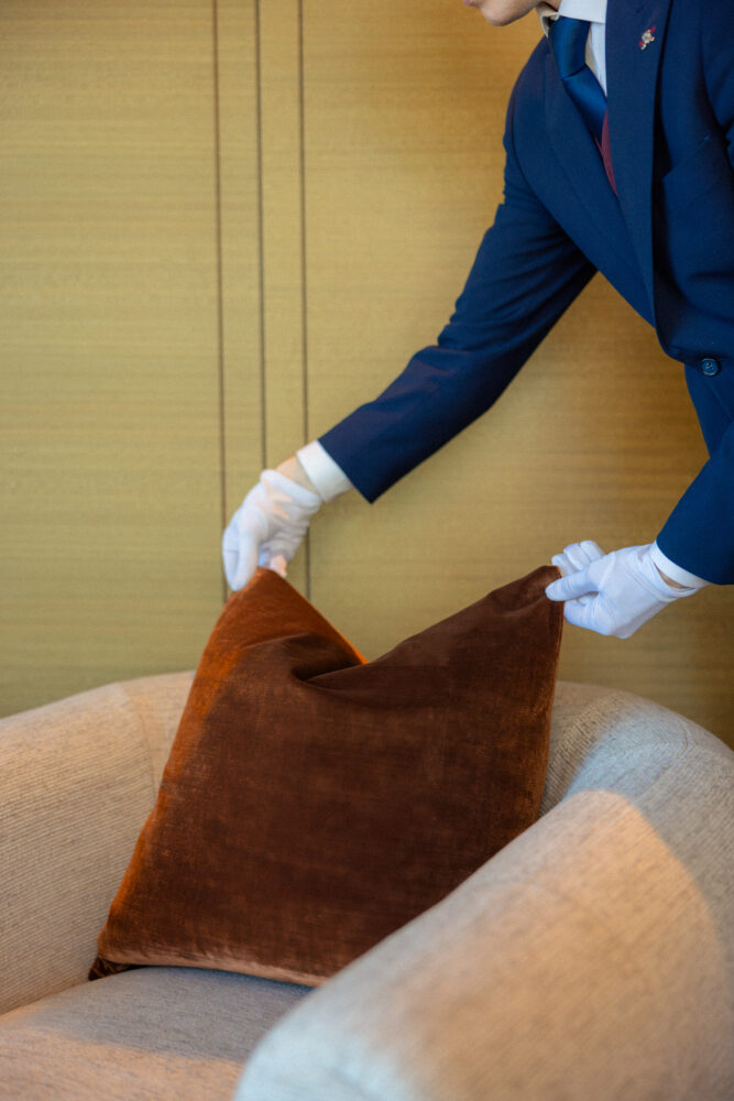 butler adjusting a pillow in a hotel room